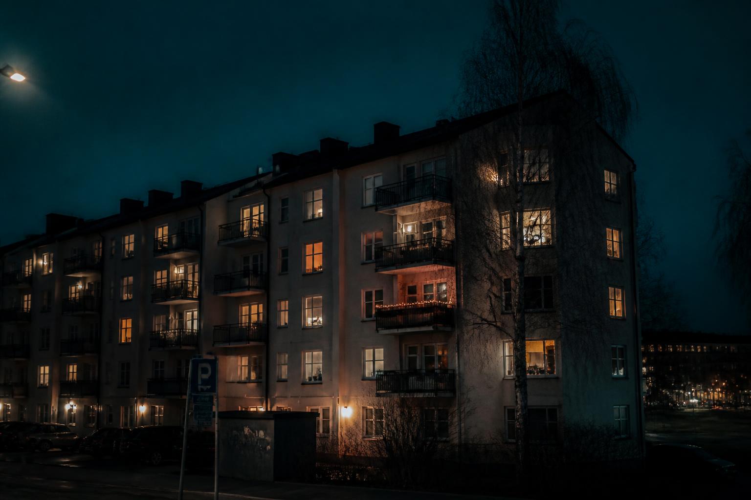 Flerfamiljshus i kvällsljus med många upplysta fönster
